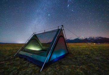Stargazing camping tent with the Milky Way above and Colorado mountains visible in the background.
