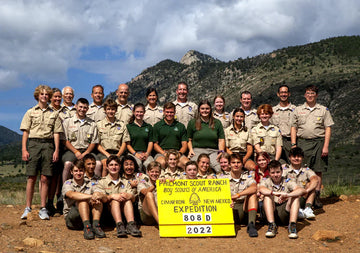 Scout troop posing for a picture in front of a mountain.